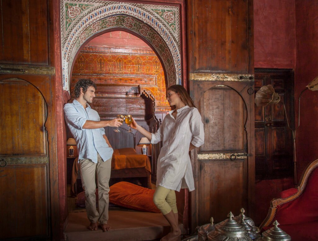 Young couple in riad making a toast in archway, Marrakesh, Morocco
